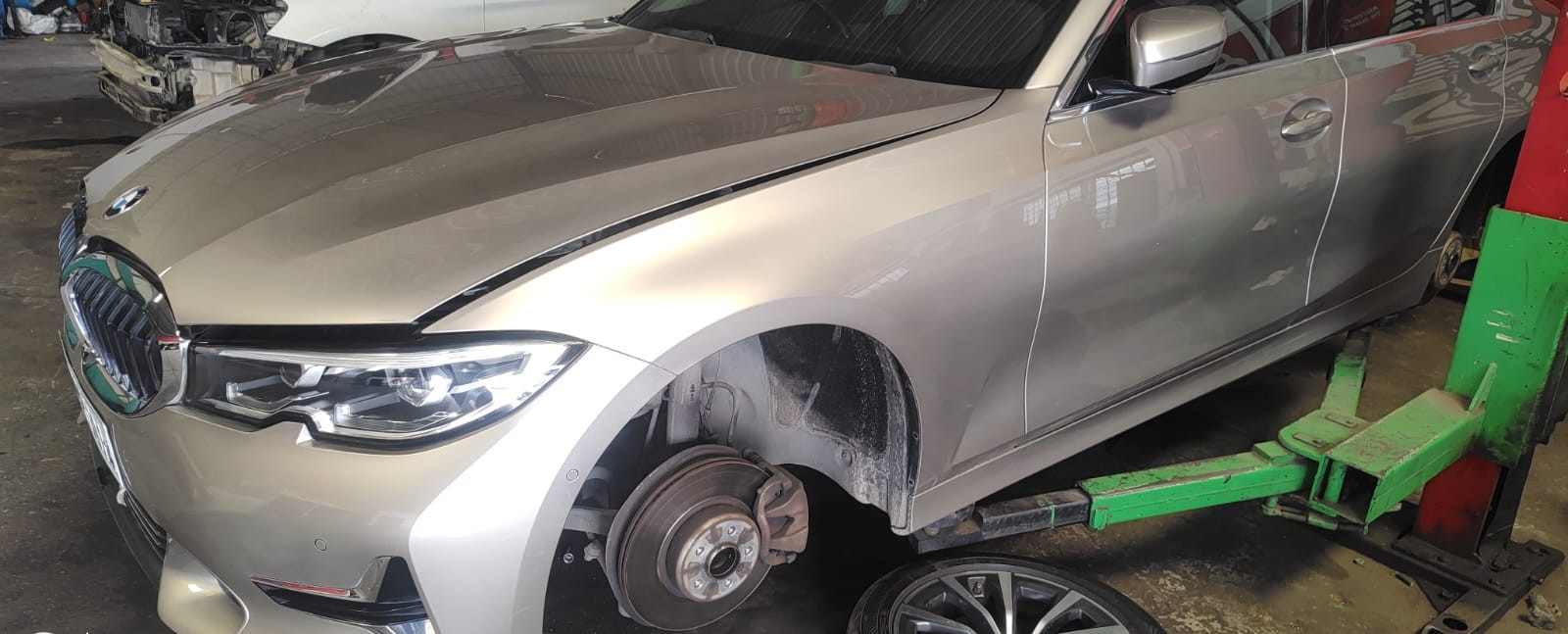 BMW 3 Series on a workshop lift with the front wheel removed and brake disc and caliper exposed, at iCarService, Hyderabad