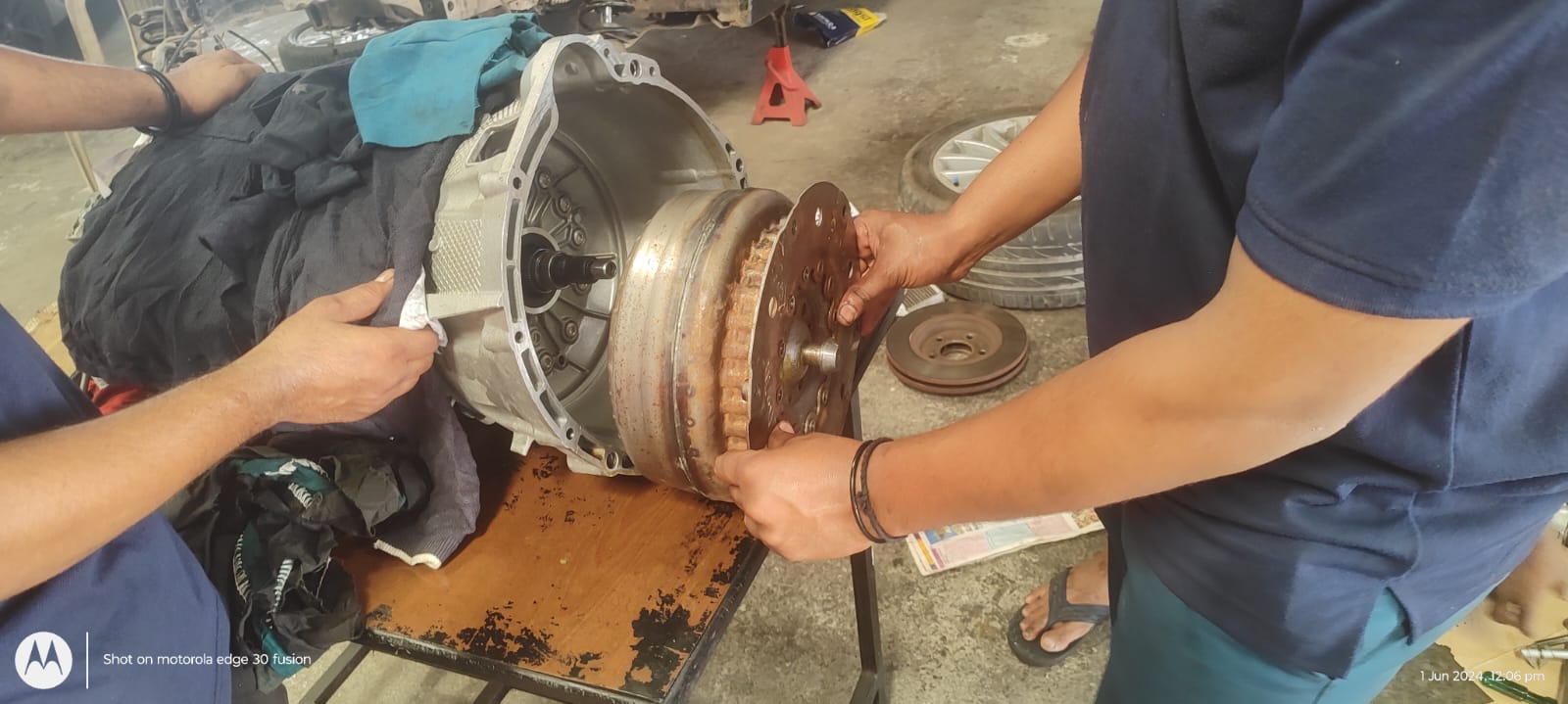 Technicians working on a vehicle transmission component at the iCarService workshop